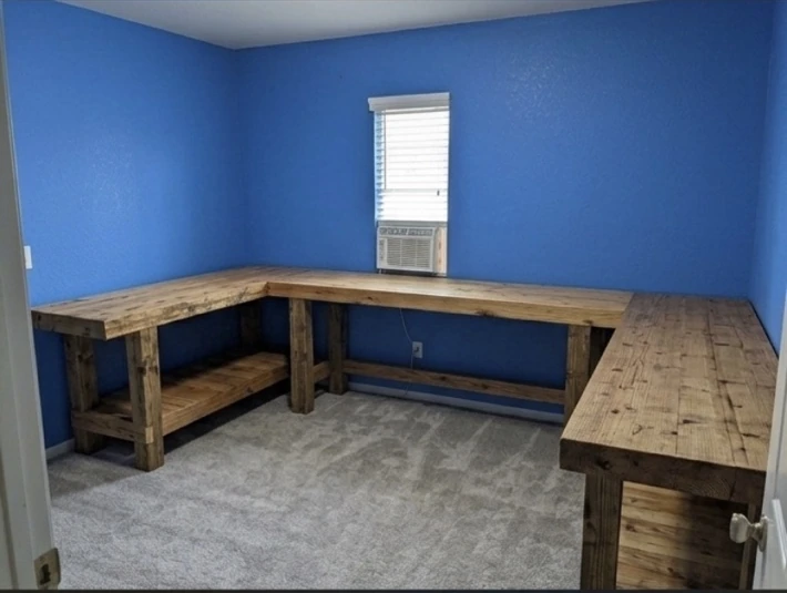 L-shaped wooden workbenches arranged along blue walls in a room